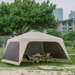 Camping gazebo set up in a park with chairs and a table underneath